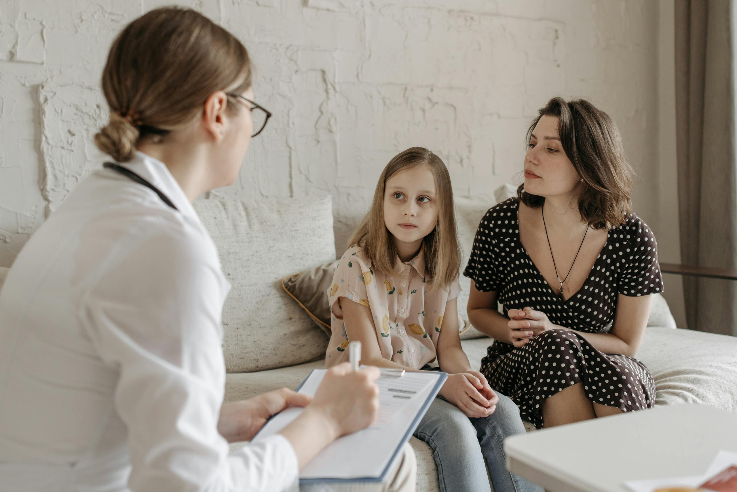 A mother and daughter consult with a doctor during a medical appointment indoors.